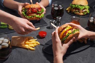 Photo of People with burgers and French fries at table, closeup