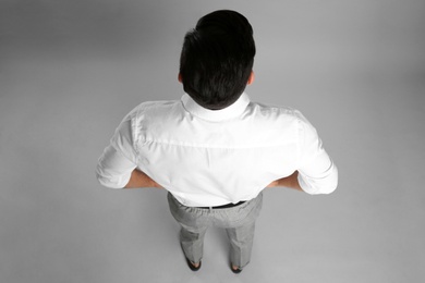 Businessman in formal clothes on grey background, back view