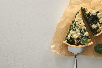 Photo of Delicious homemade spinach quiche on white table, top view. Space for text