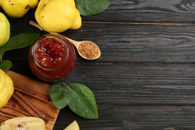 Delicious quince jam and fruits on black wooden table, flat lay. Space for text