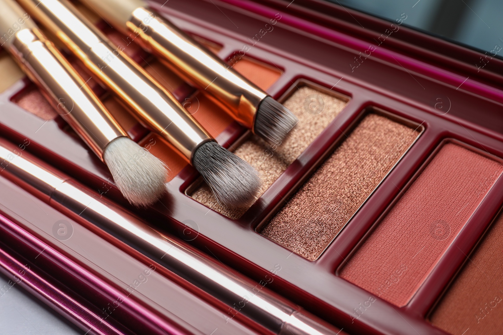 Photo of Beautiful eye shadow palette with brushes on white table, closeup