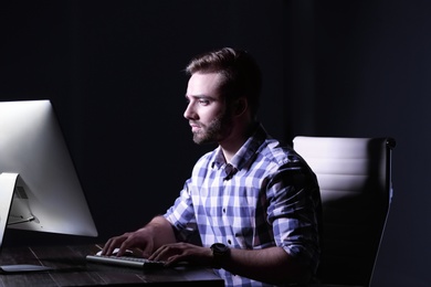 Photo of Concentrated young man working in office alone at night