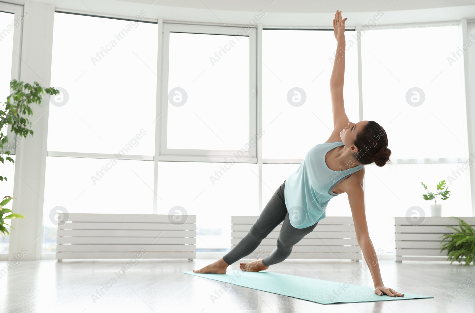 Photo of Young woman practicing side plank asana in yoga studio. Vasisthasana pose