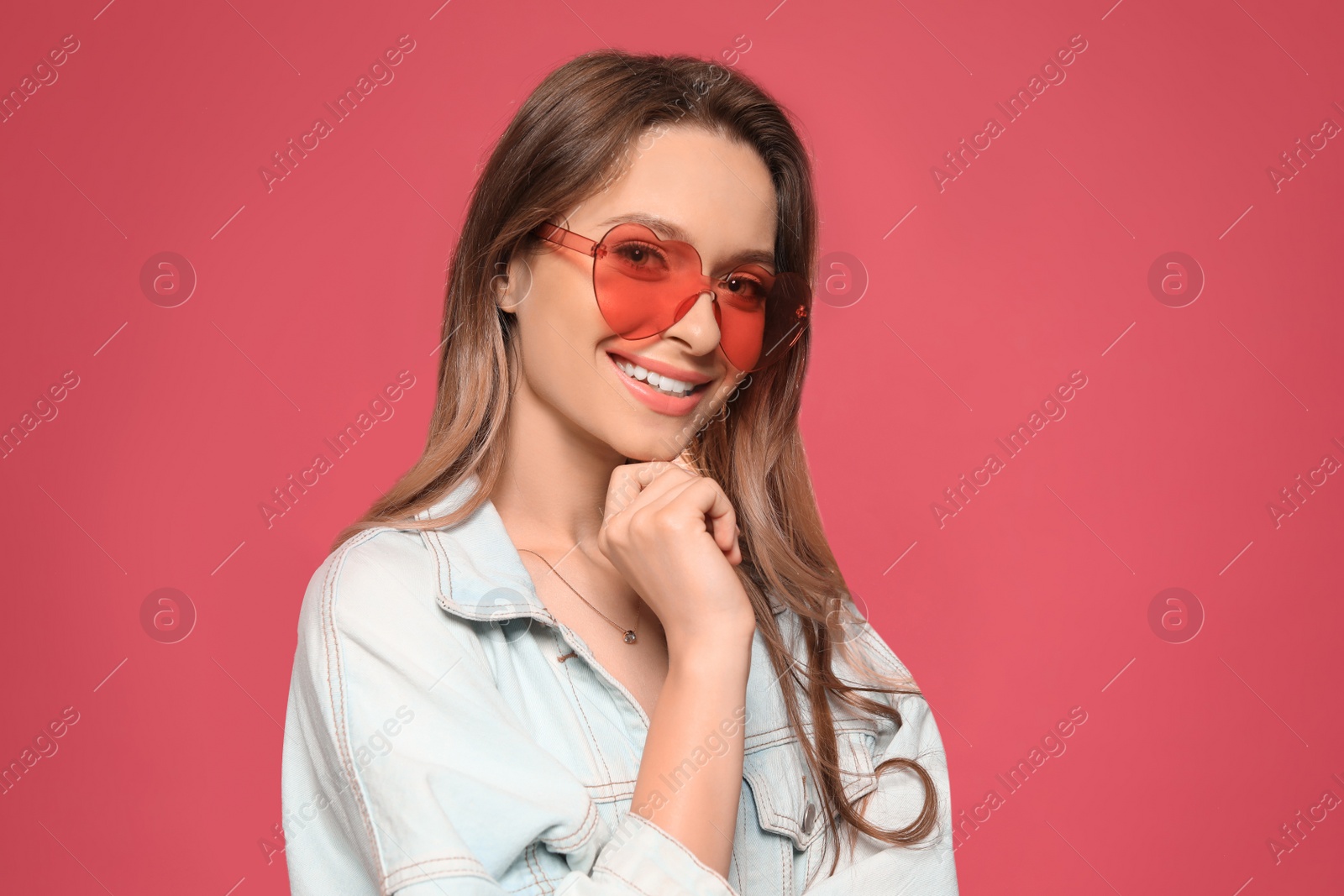 Photo of Portrait of beautiful young woman with heart shaped sunglasses on color background