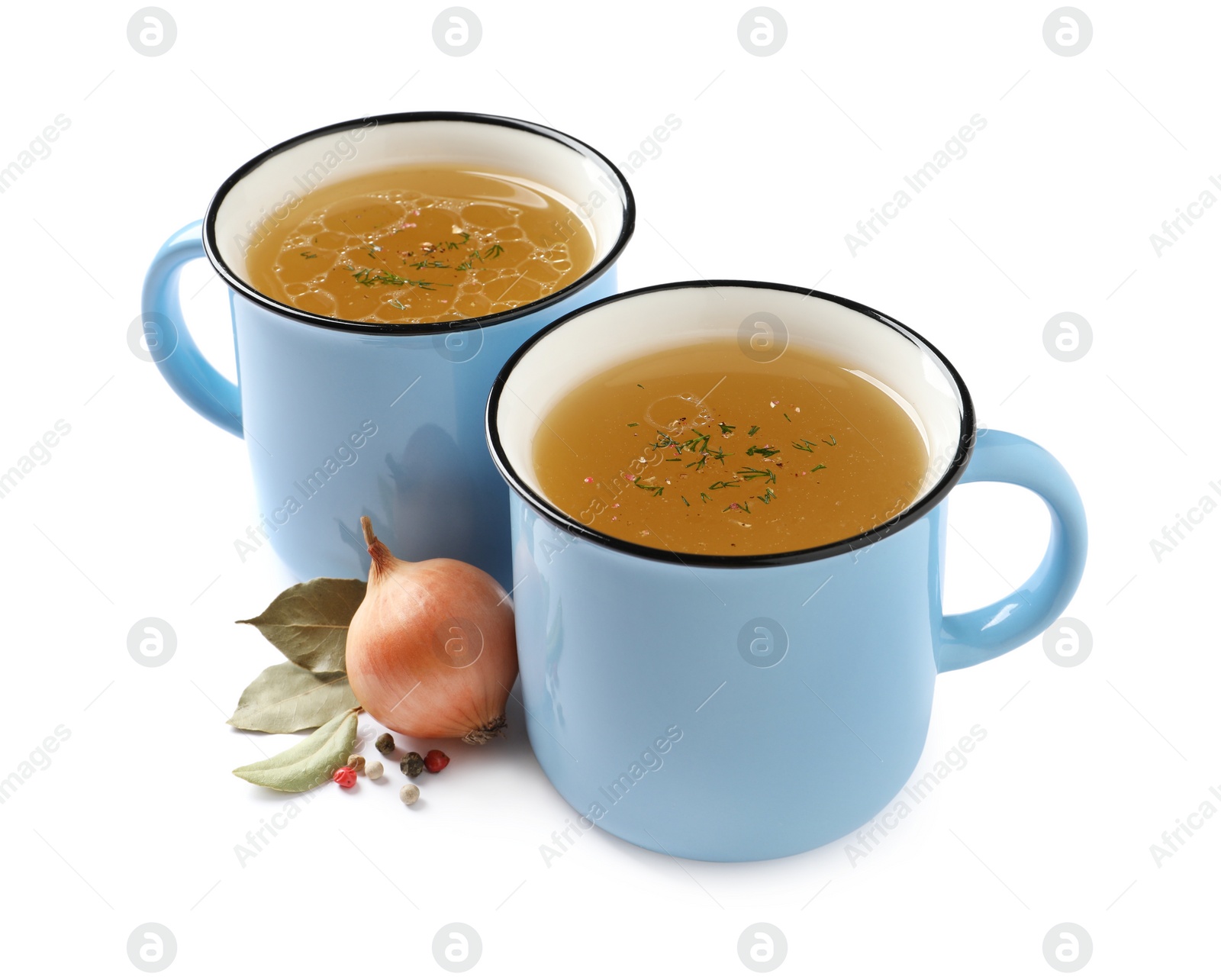 Photo of Hot delicious bouillon in cups and ingredients on white background