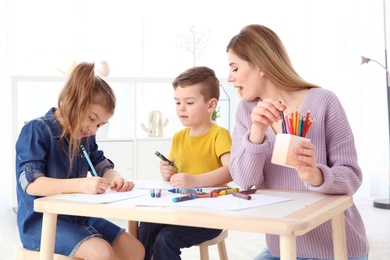 Photo of Cute little children and their nanny drawing at home