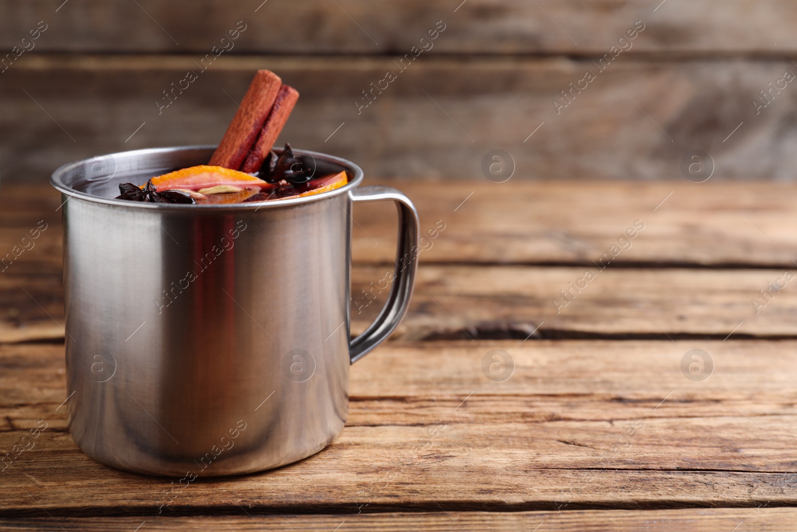 Photo of Aromatic mulled wine on wooden table, space for text