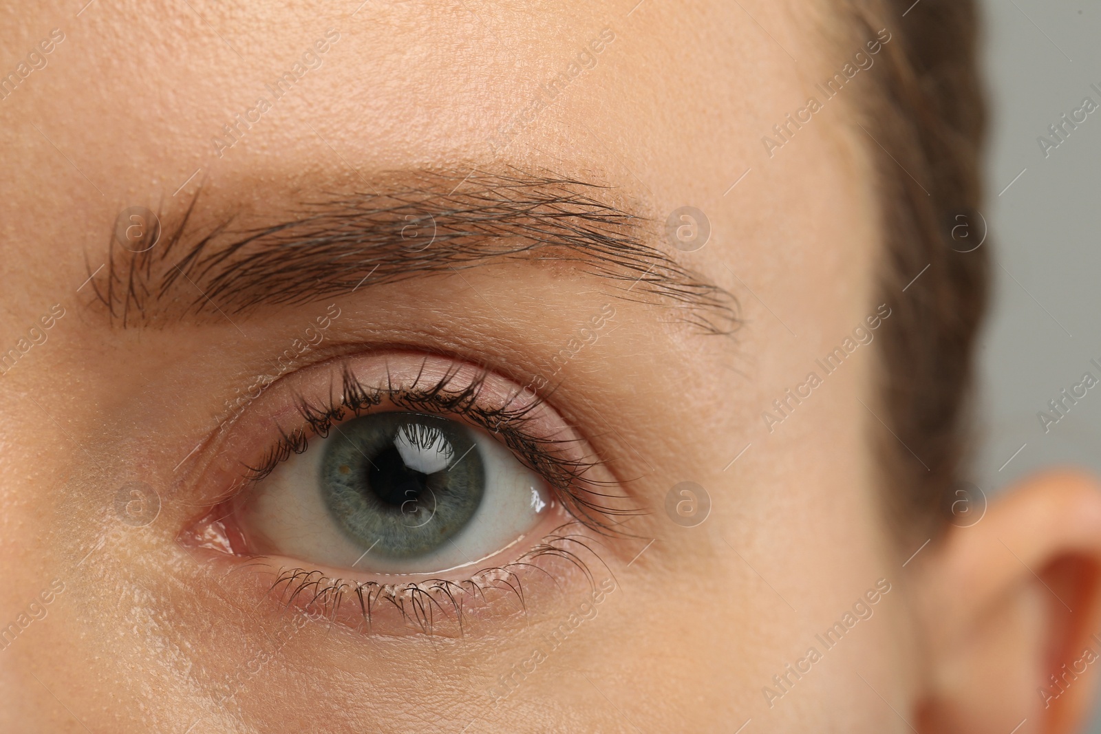 Photo of Woman with beautiful natural eyelashes on grey background, closeup