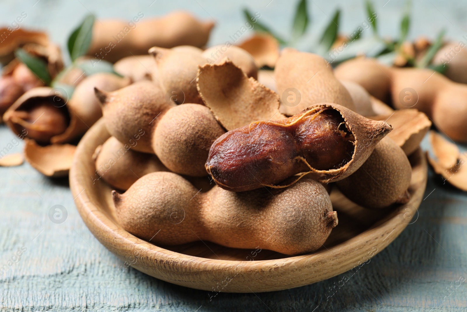 Photo of Plate with delicious ripe tamarinds on blue wooden table, closeup