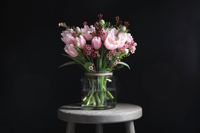 Photo of Beautiful bouquet with spring pink tulips on wooden table against black background