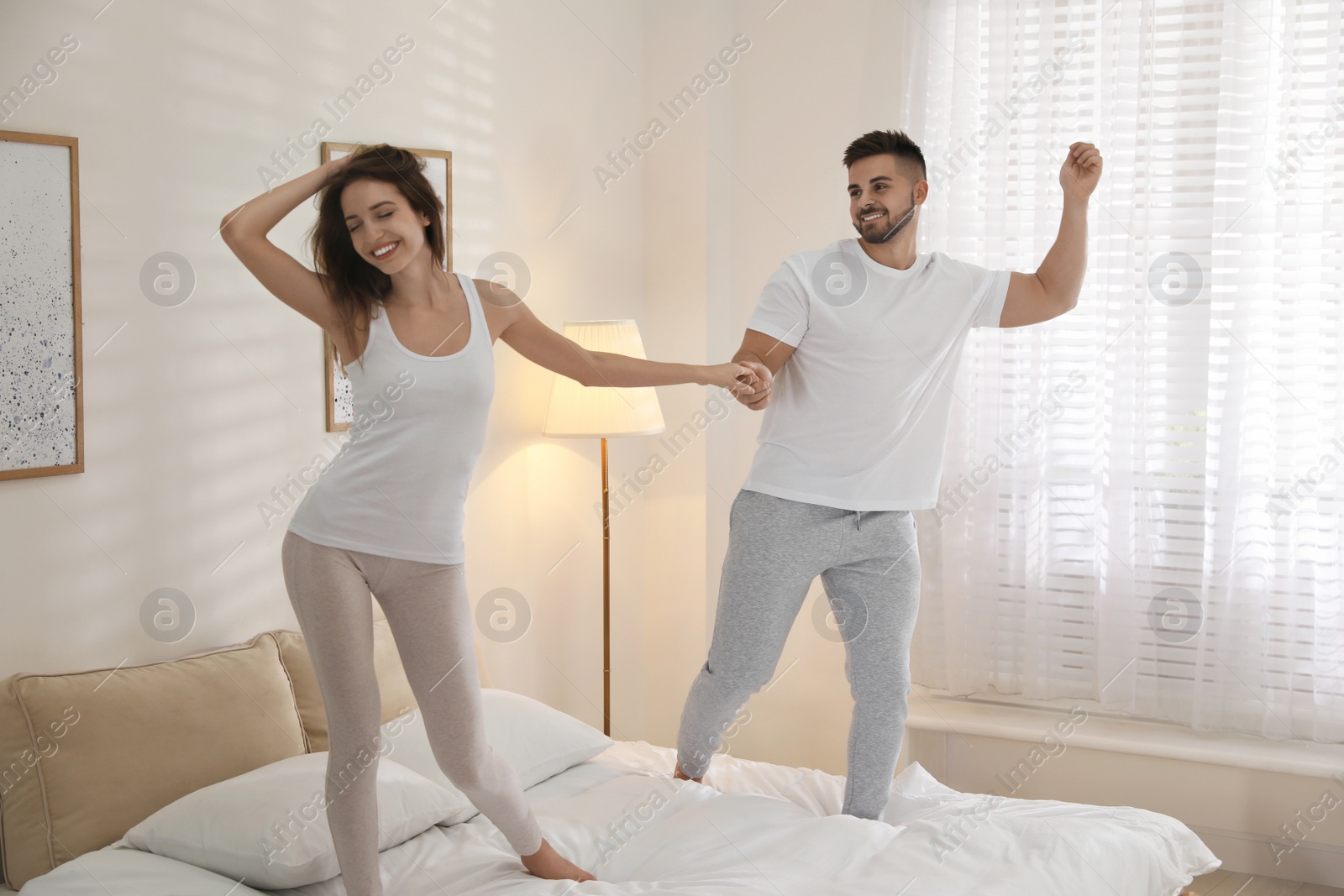 Photo of Lovely young couple dancing on bed at home