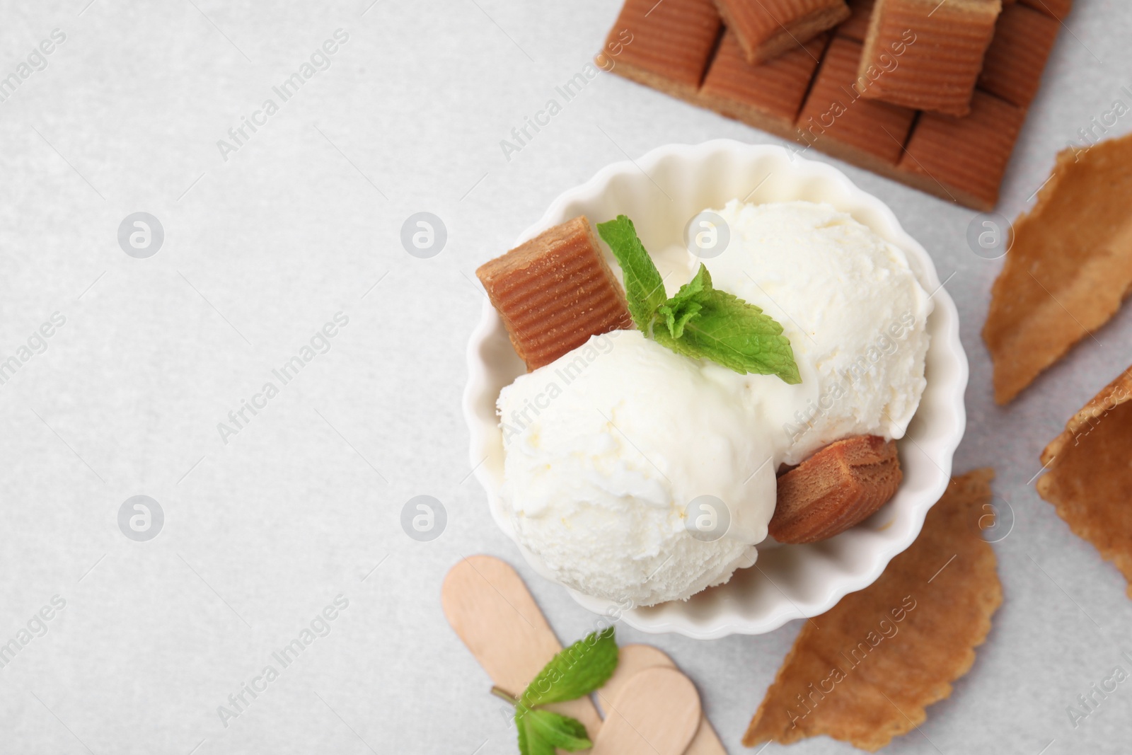 Photo of Scoops of tasty ice cream with mint and caramel candies on white table, flat lay. Space for text