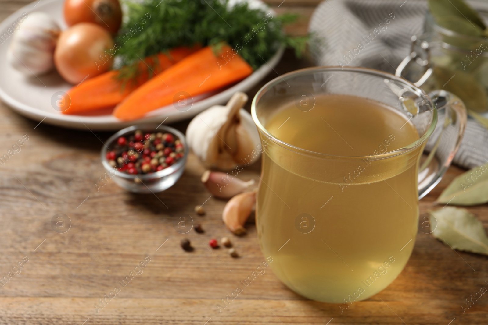 Photo of Hot delicious bouillon in glass cup on wooden table. Space for text