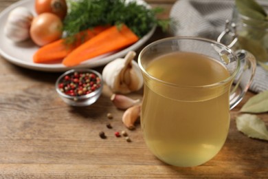 Hot delicious bouillon in glass cup on wooden table. Space for text