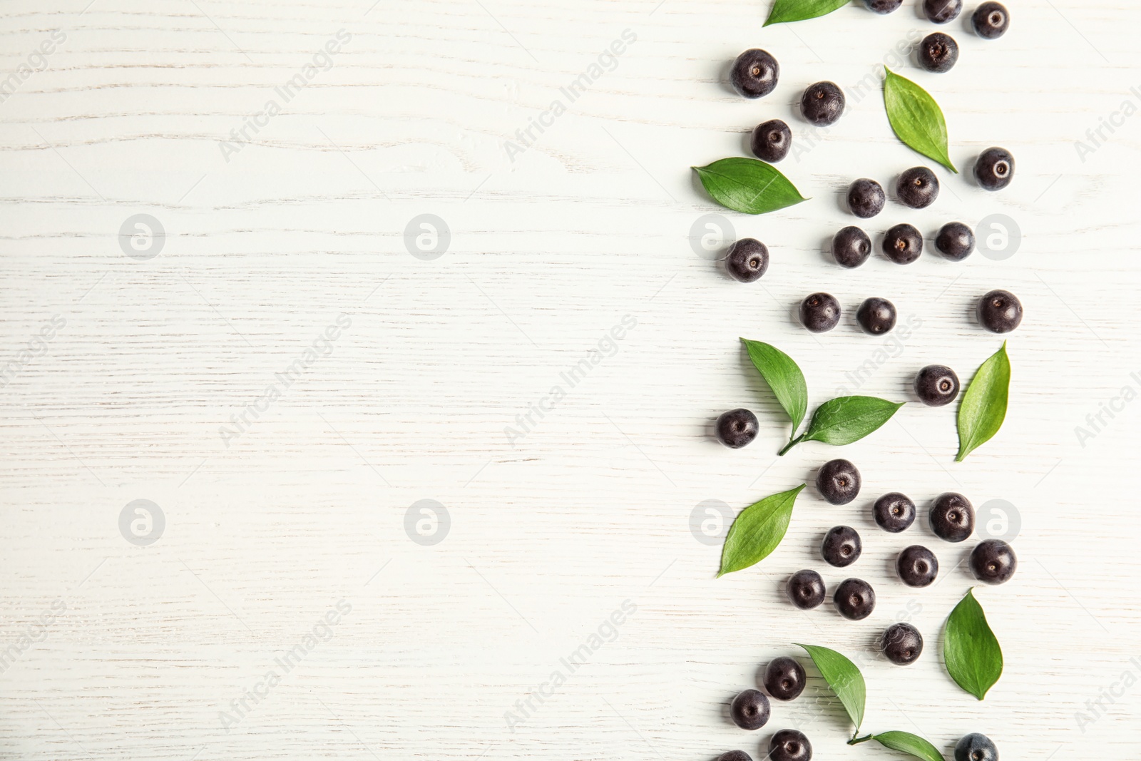 Photo of Flat lay composition with fresh acai berries and leaves on wooden background