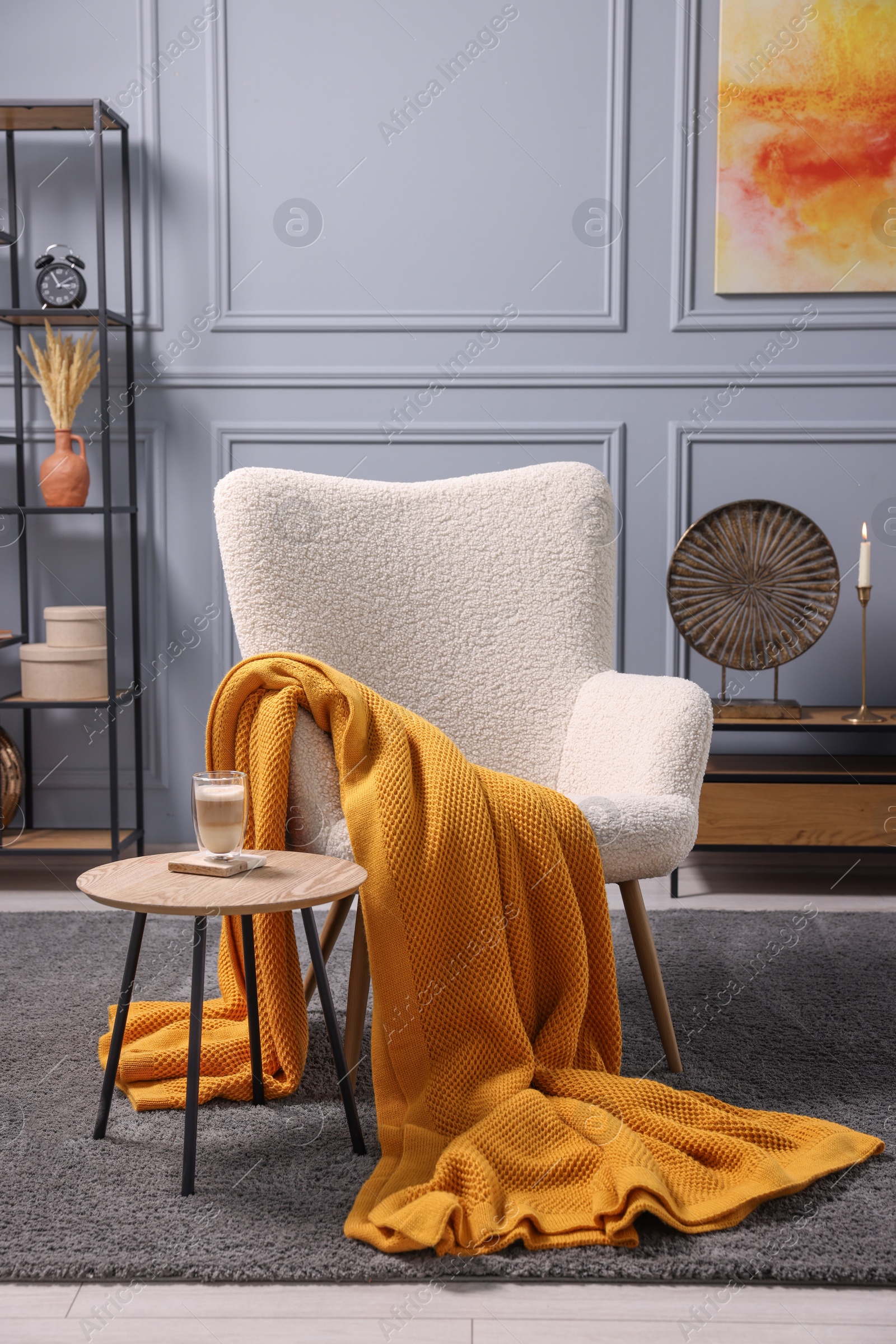 Photo of Living room interior with comfortable armchair, blanket and side table