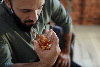 Photo of Man with glass of whiskey indoors, closeup