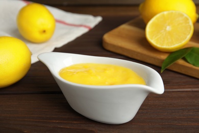 Delicious lemon curd in sauce boat on wooden table