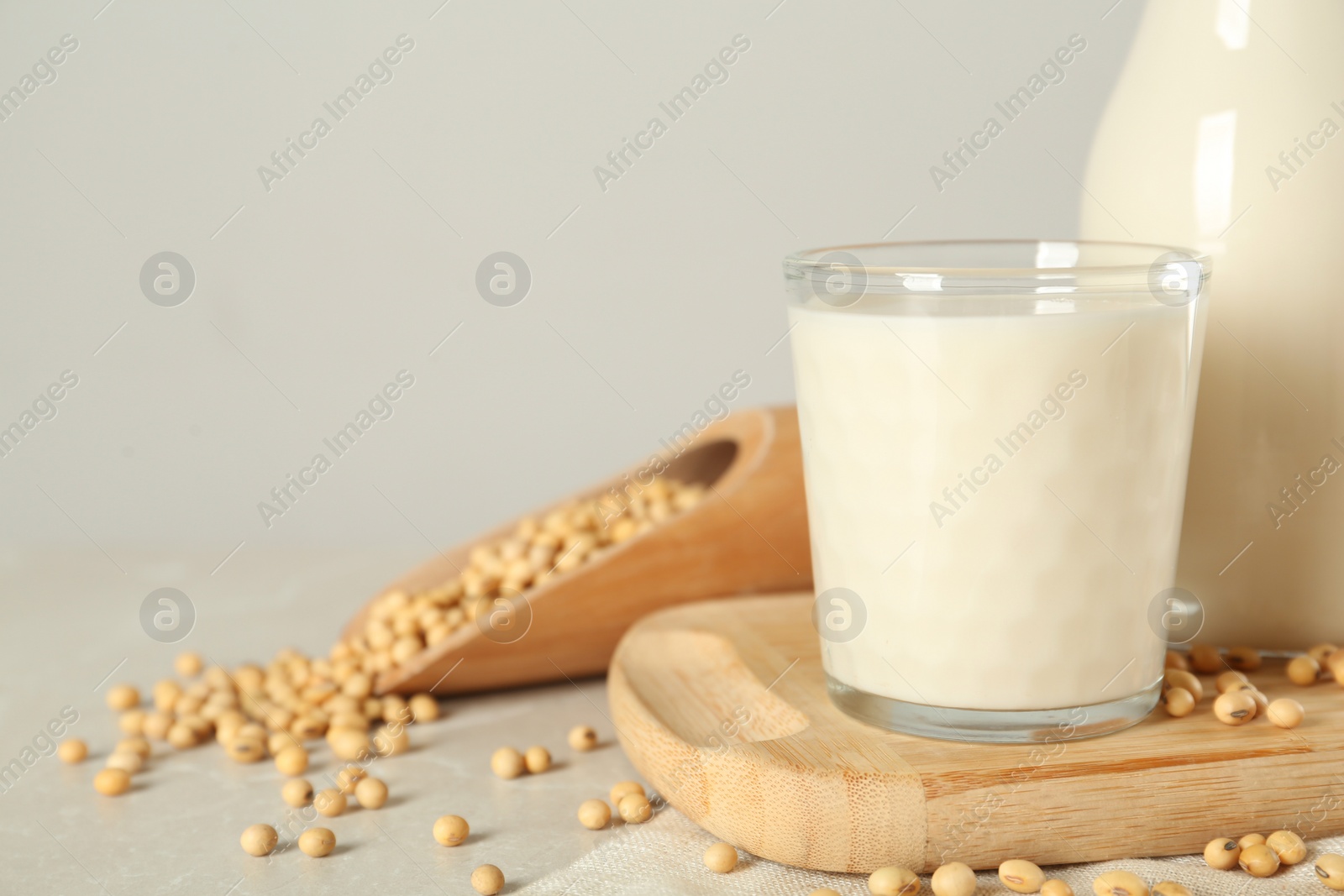 Photo of Fresh soy milk and beans on light grey table. Space for text