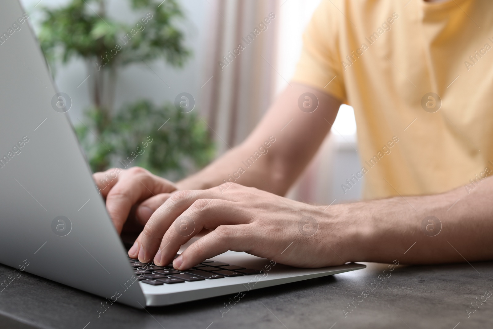 Photo of Young man working with laptop at desk in home office, closeup