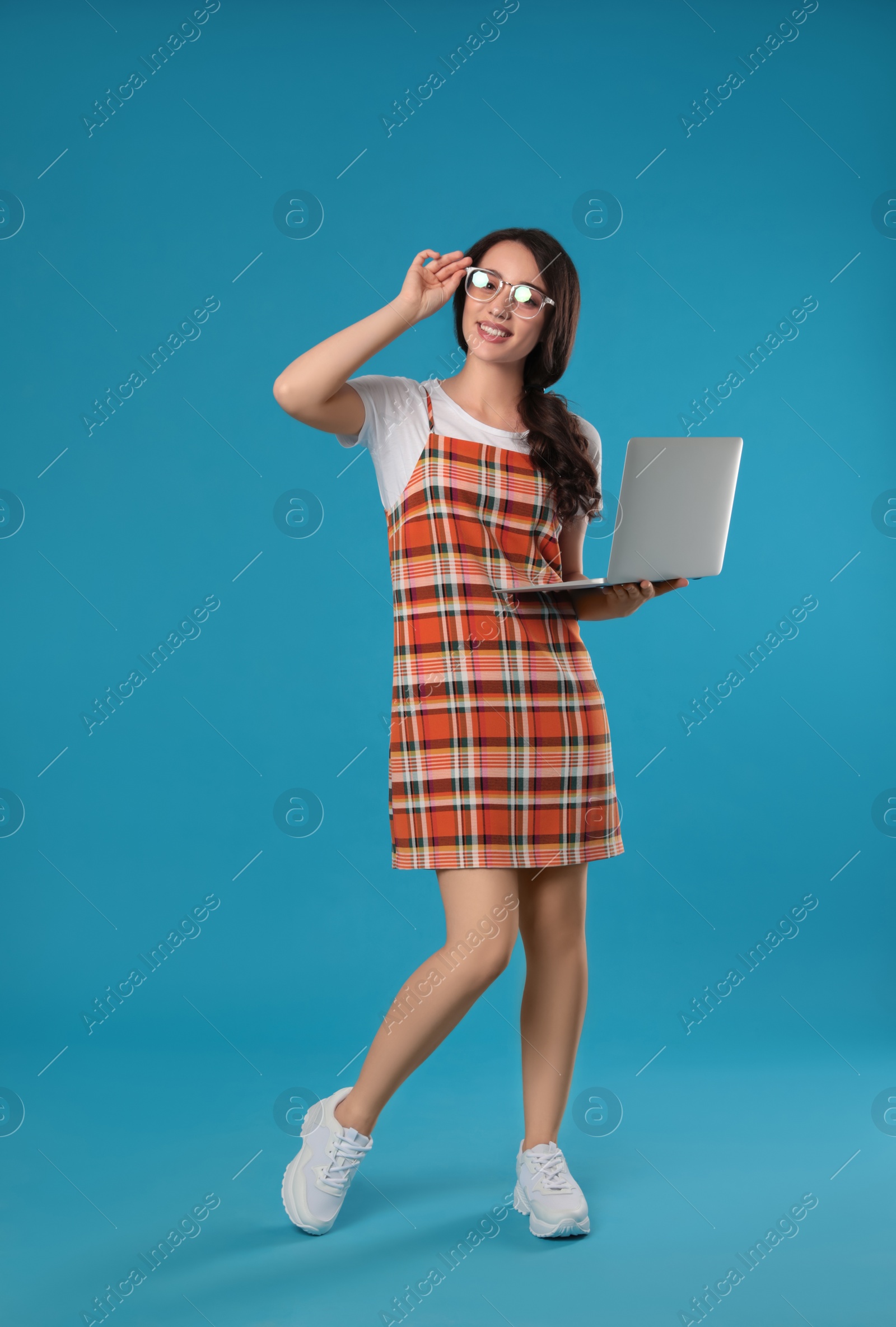 Photo of Young woman with laptop on blue background