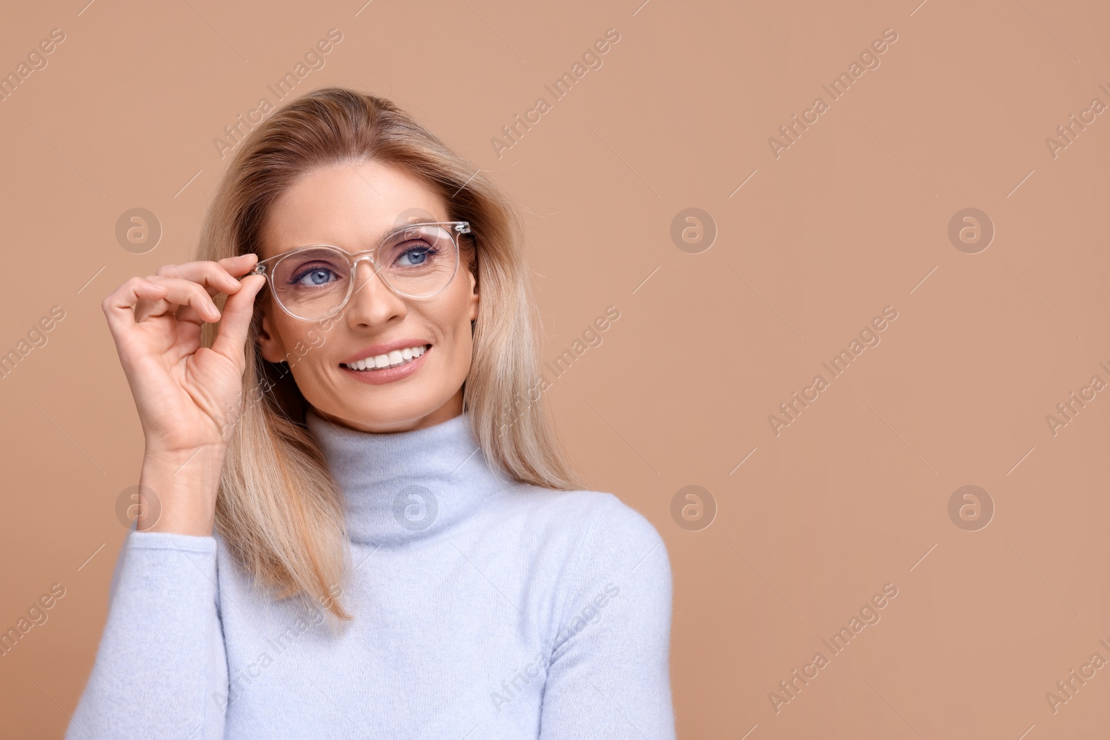 Photo of Portrait of smiling middle aged woman in glasses on beige background. Space for text