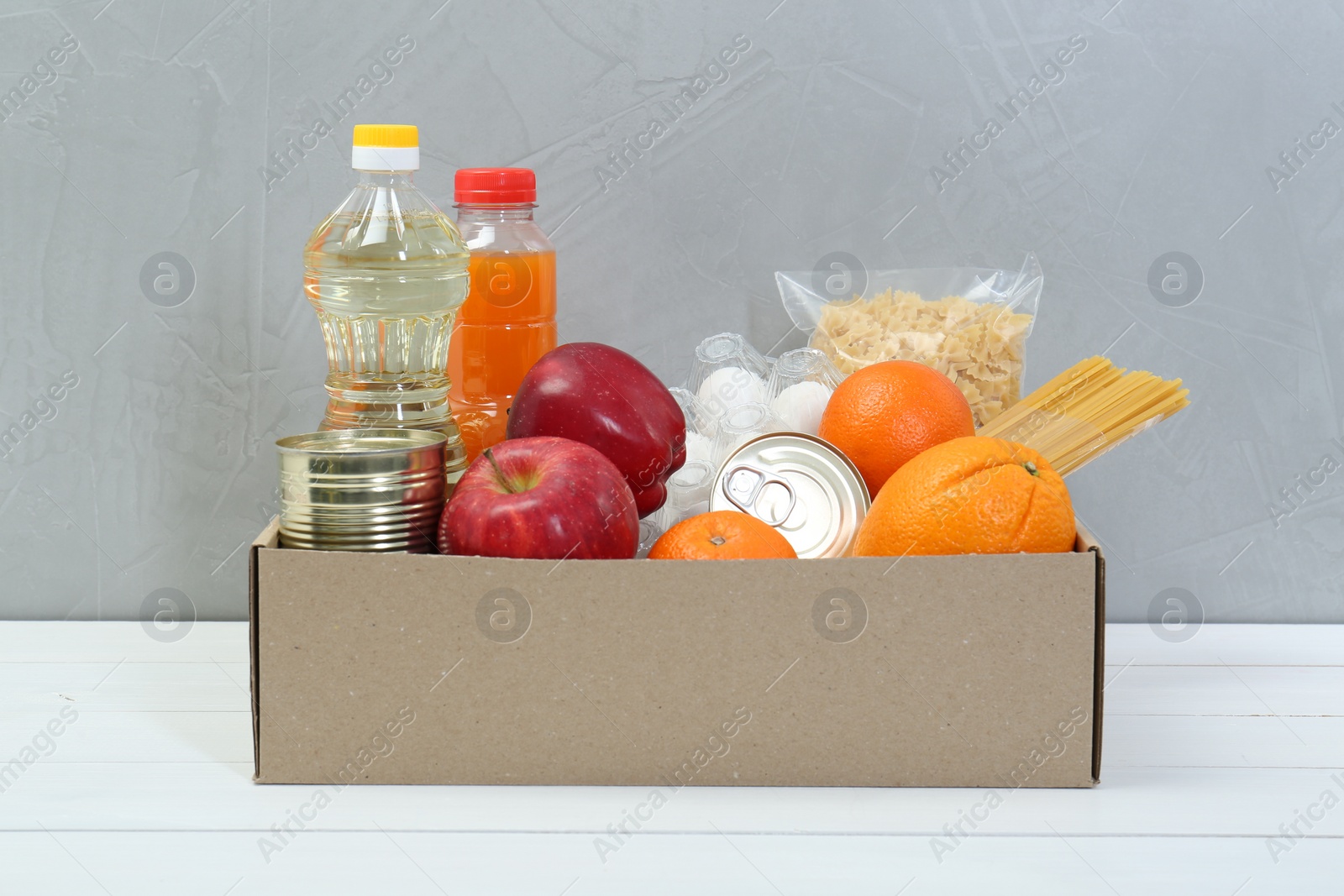 Photo of Humanitarian aid. Different food products for donation in box on white wooden table