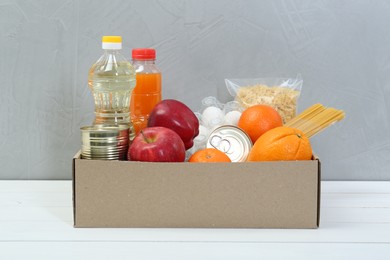 Humanitarian aid. Different food products for donation in box on white wooden table