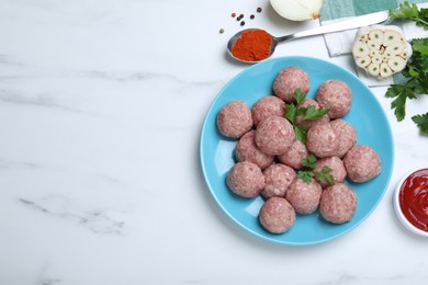 Many fresh raw meatballs and ingredients on white table, flat lay. Space for text