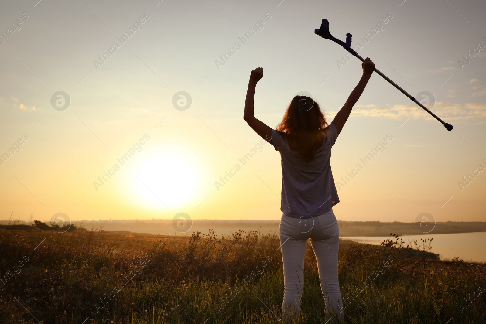 Photo of Woman holding elbow crutch outdoors at sunrise, back view. Healing miracle