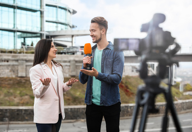 Image of Young journalist interviewing businesswoman on city street