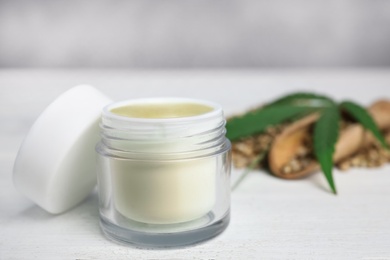 Photo of Jar of hemp cream on white wooden table against blue background, space for text. Organic cosmetics