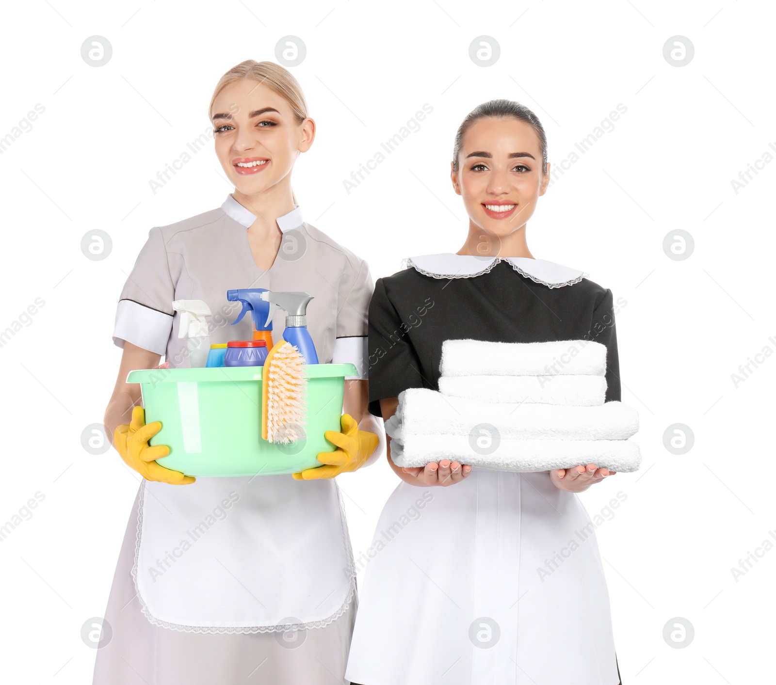 Photo of Young chambermaids with folded clean towels and detergents on white background