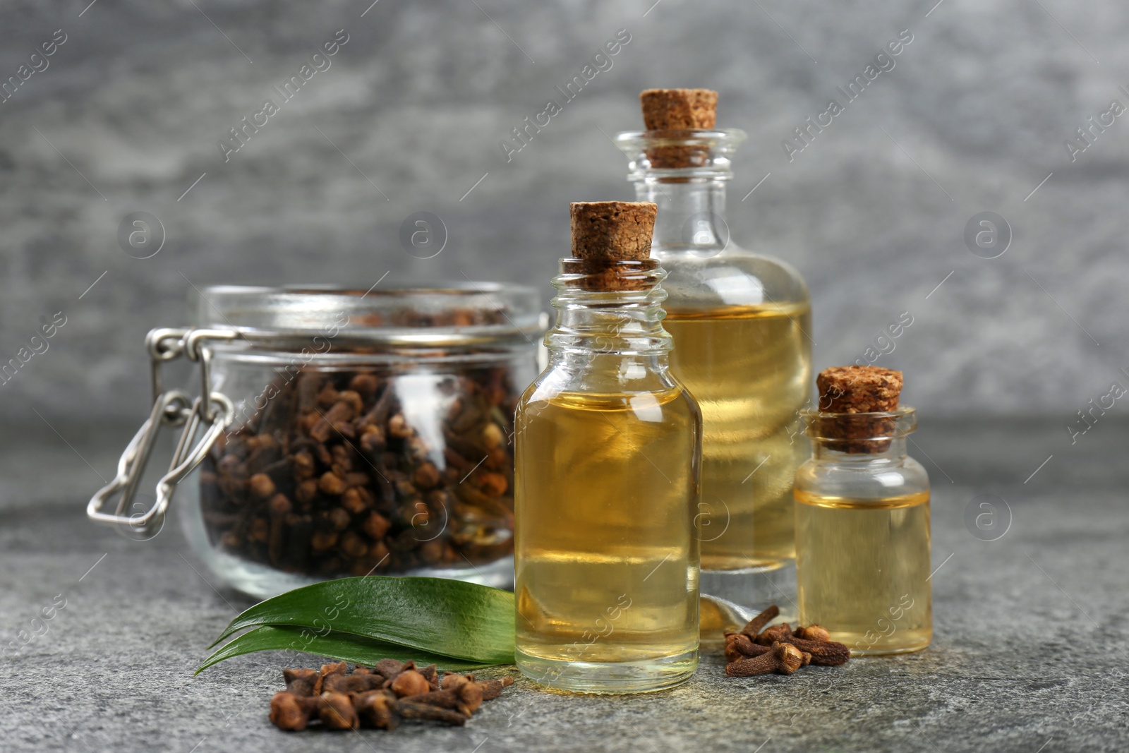 Photo of Essential oil and dried cloves on grey stone table