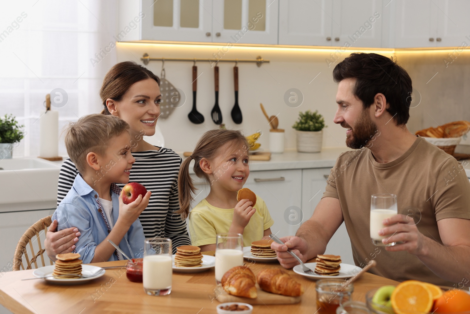 Photo of Happy family having breakfast at table in kitchen