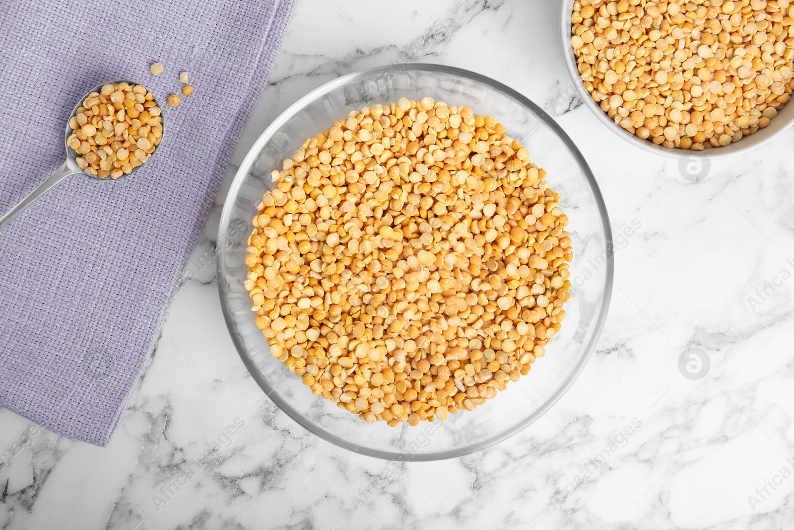 Photo of Bowls and spoon with dried peas on marble background, top view