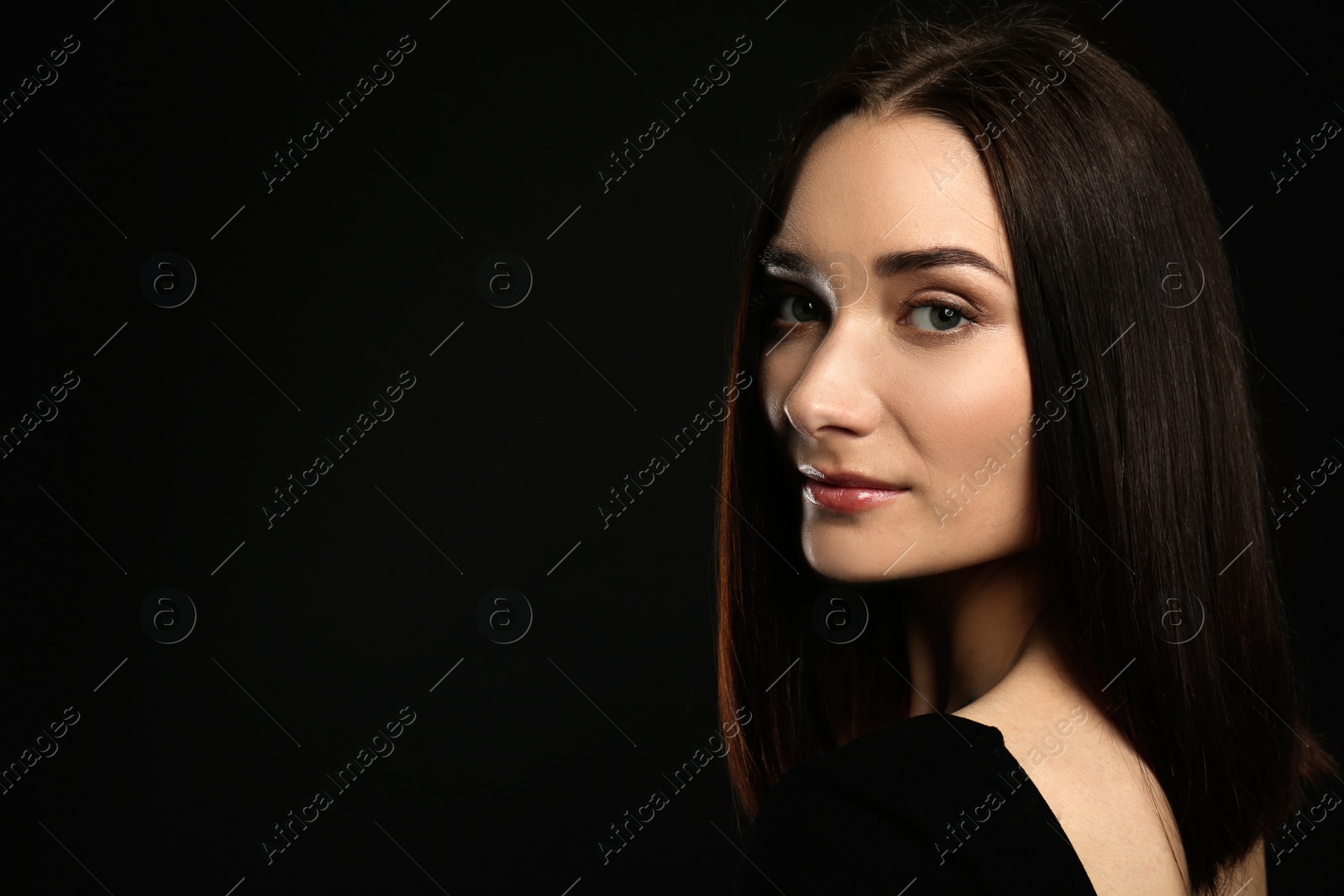 Photo of Portrait of pretty young woman with gorgeous chestnut hair on black background, space for text