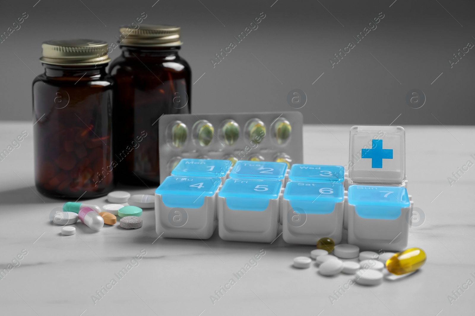 Photo of Weekly pill box with medicaments on white marble table