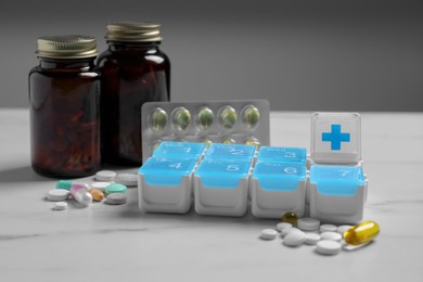 Weekly pill box with medicaments on white marble table