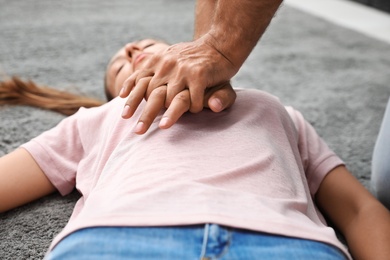 Photo of Man performing CPR on unconscious young woman indoors, closeup. First aid