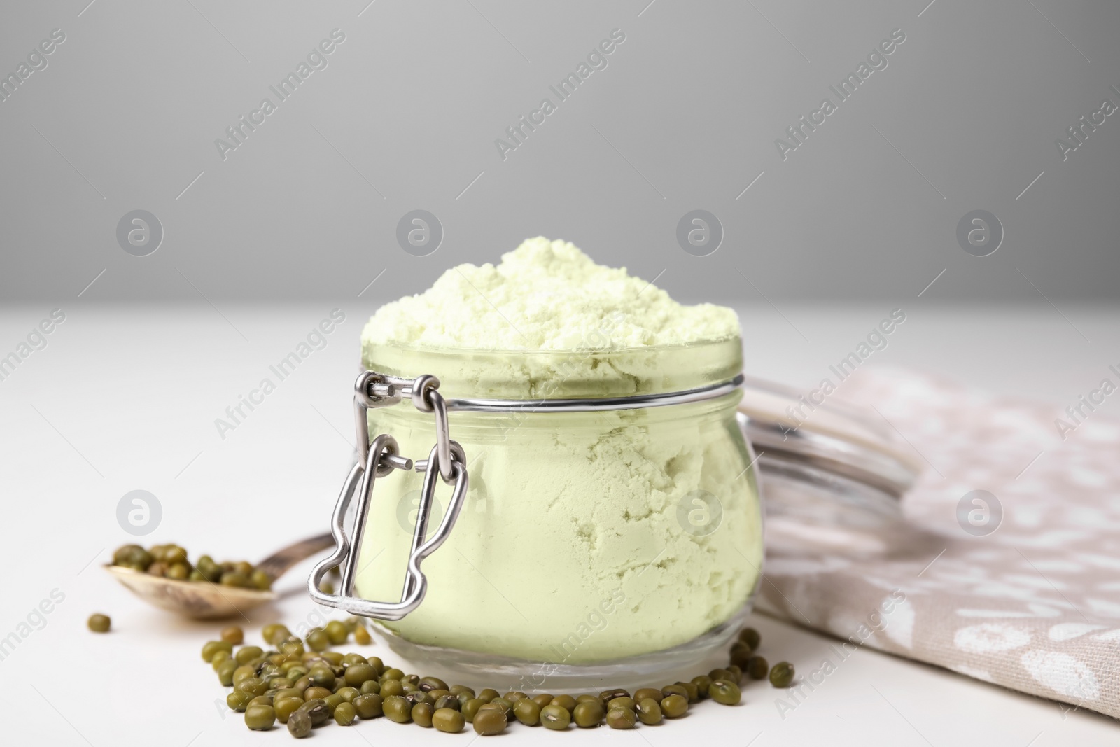 Photo of Glass jar of flour and mung beans on white table