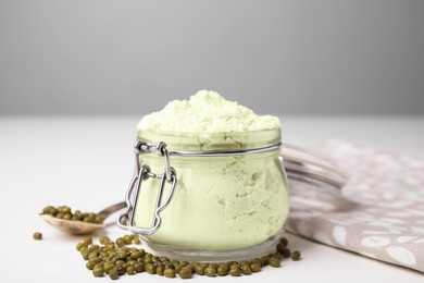 Photo of Glass jar of flour and mung beans on white table