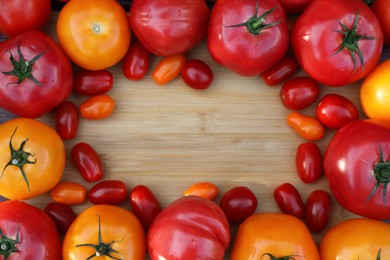 Photo of Frame with different sorts of tomatoes on wooden table, flat lay. Space for text