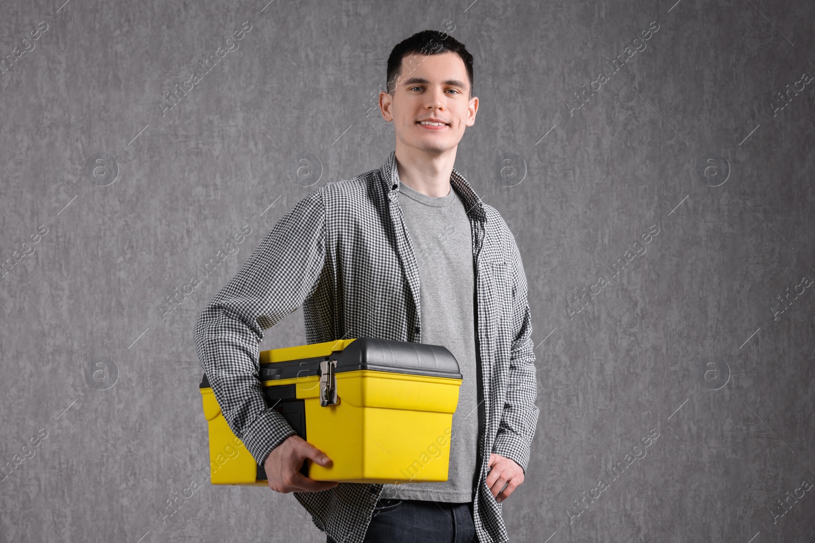 Photo of Young man with tool box on grey background