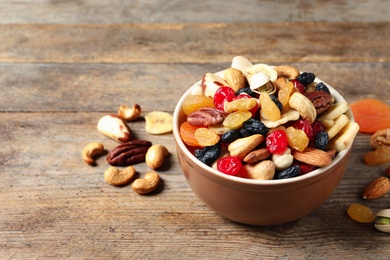 Bowl with different dried fruits and nuts on table. Space for text