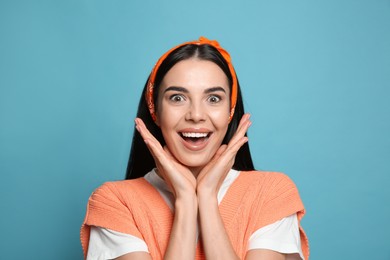 Young woman wearing stylish bandana on light blue background