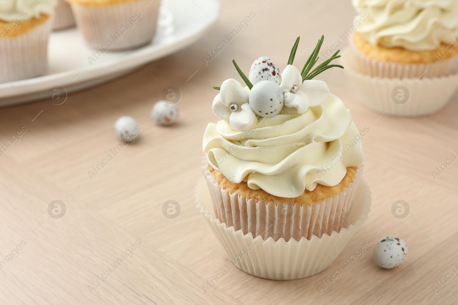 Photo of Tasty Easter cupcakes with vanilla cream on wooden table, closeup