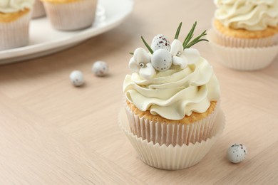 Tasty Easter cupcakes with vanilla cream on wooden table, closeup