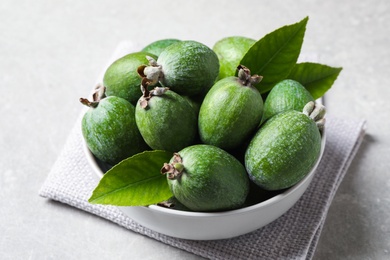 Delicious fresh feijoas in bowl on light grey table, closeup