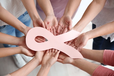 Photo of Women holding pink paper ribbon, above view. Breast cancer awareness concept